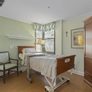 A tidy hospital room with a bed, chair, and window.