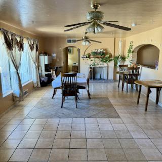 A spacious and well-lit living area featuring a dining table, ceiling fan, and tiled flooring.