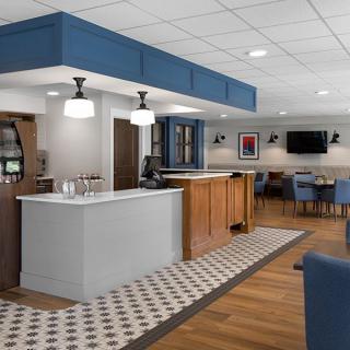 A modern lobby with a reception desk and seating area, featuring blue accents and stylish lighting fixtures.