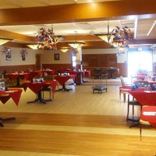 A spacious and elegantly arranged restaurant interior with red tablecloths.