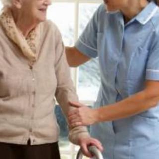 A caregiver assists an elderly person using a walker.