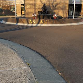 A view of a building entrance with curved pavement and shadows in the afternoon light.