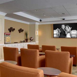 A modern lounge area with comfortable seating and a large screen for presentations.