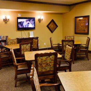 A cozy dining area with multiple tables and chairs, featuring a wall-mounted television and elegant decor.