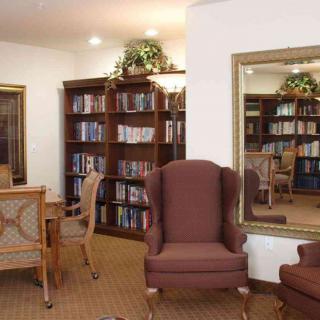 A cozy library corner with armchairs, bookshelves, and a large mirror.