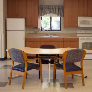 A kitchen area with a table, chairs, refrigerator, and oven.