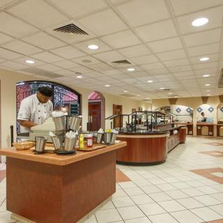 A spacious buffet restaurant with a chef preparing food at a central station.