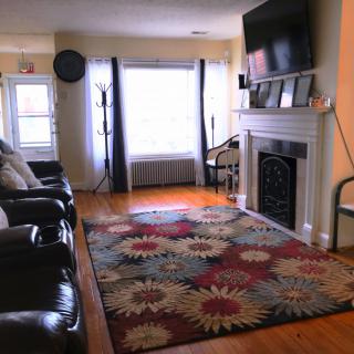 A cozy living room featuring a colorful rug, leather sofas, and a fireplace with a television mounted above.