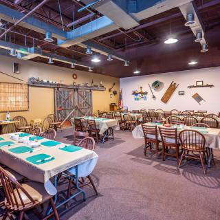 A cozy restaurant dining area with neatly arranged tables and chairs, featuring rustic decor on the walls.