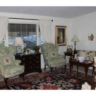 A cozy living room featuring floral armchairs, a patterned rug, and elegant decor.