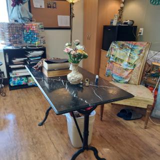 A cozy workspace featuring a table with a flower vase and a chair, alongside shelves filled with books and materials.