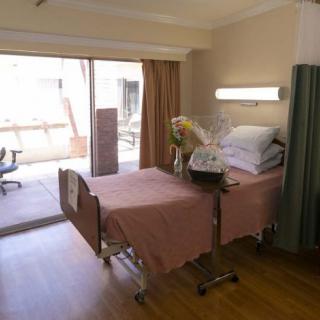 A hospital room with a single bed and a view of the outdoors.