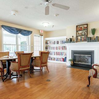 A cozy living and dining space with bookshelves, a fireplace, and hardwood flooring.