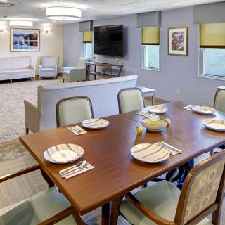 A cozy dining room setup with a table set for six, adjacent to a comfortable living area with a television.