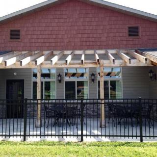 A building with a pergola-covered patio and fenced outdoor seating area.