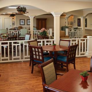 A cozy dining area with wooden tables and chairs, decorated with plants and artwork.