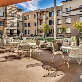 A stylish outdoor lounge area in a modern apartment complex, featuring comfortable seating and landscaped grounds.