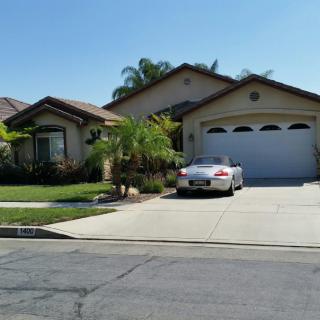 A suburban house with a car parked in the driveway on a sunny day.