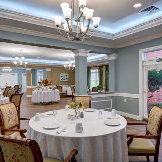 An elegant dining room with formal table settings and chandeliers.