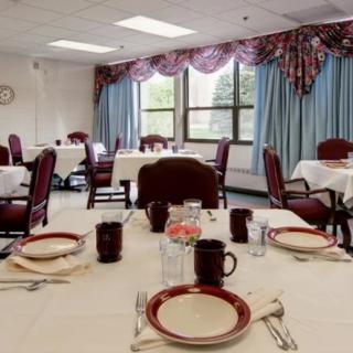 A neatly arranged dining room with tables set for a meal, featuring elegant tableware and comfortable chairs.