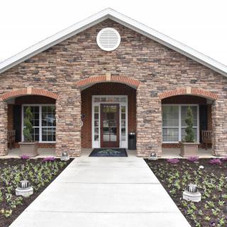 A brick house with a symmetrical entrance, featuring two windows and a landscaped walkway.