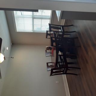 A dining room with a wooden table and chairs, featuring a window and wood flooring.