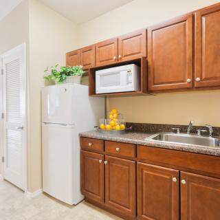 A modern kitchen featuring wooden cabinets, a refrigerator, microwave, and sink.