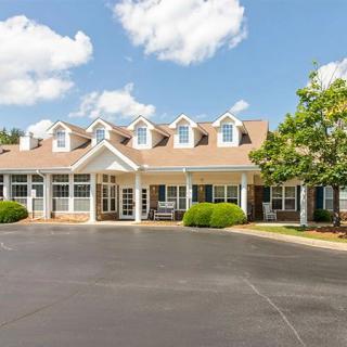 A suburban residential building with a neatly landscaped entry and a spacious driveway under a partly cloudy sky.
