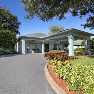 A charming entrance to a well-maintained building, surrounded by lush landscaping on a sunny day.