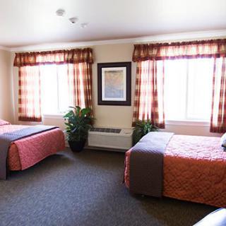 A hotel room with two beds, large windows, and elegant decor.