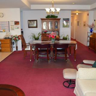 A cozy living and dining area with carpeted flooring and a wooden dining set.