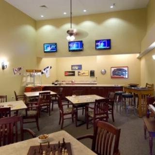 An indoor cafe with tables, chairs, and multiple televisions.
