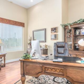 A well-organized home office with a wooden desk, computer, and bookshelf.
