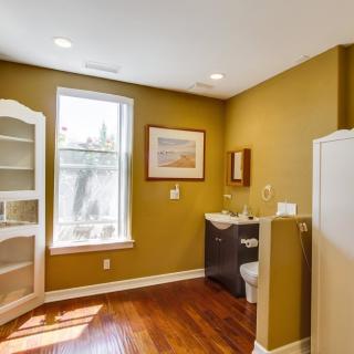 A cozy bathroom with wooden floors, featuring a sink, toilet, and built-in shelves.
