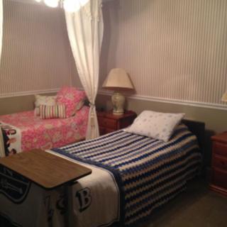 A cozy bedroom with two twin beds, featuring striped bedding and a curtain divider.