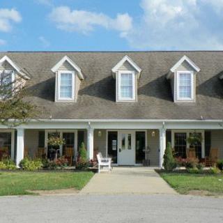 A two-story suburban house with multiple dormer windows and a manicured lawn.