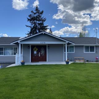 A welcoming home with a well-kept lawn under a partly cloudy sky.