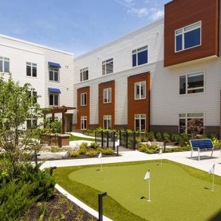 A modern residential building with a landscaped courtyard and putting green.