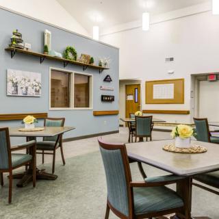 A cozy dining area with neatly arranged tables and chairs, decorated walls, and soft lighting.