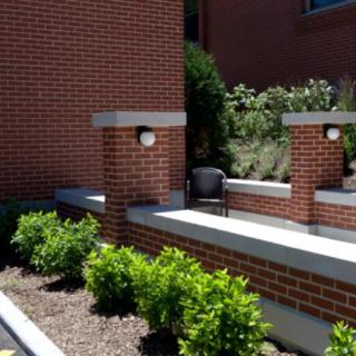 A brick building with outdoor seating and surrounding greenery.