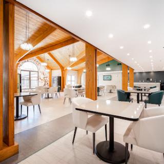 A spacious and modern dining area featuring wooden beams and bright lighting.
