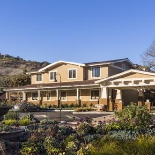 A beautiful two-story house surrounded by a well-maintained garden and scenic landscape.