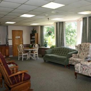 A cozy living room with upholstered chairs, a sofa, and a dining table near large windows.
