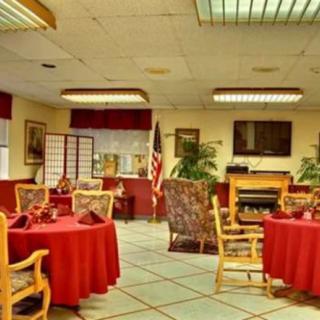 A cozy dining area with red tablecloths, wooden chairs, and decorative plants.