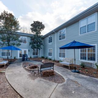 A serene outdoor courtyard with benches and blue umbrellas next to a residential building.
