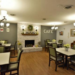 A cozy cafe interior with tables, chairs, and a fireplace.