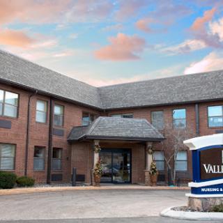 A welcoming residential facility with a landscaped entrance, set against a beautiful sky.