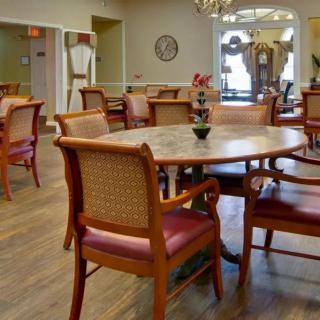 A spacious dining area with wooden tables and chairs arranged neatly on polished wood flooring.