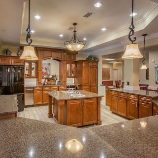 A spacious, modern kitchen featuring wood cabinetry, a central island, and elegant pendant lighting.