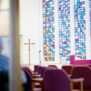 Interior view of a church with stained glass windows and seating.